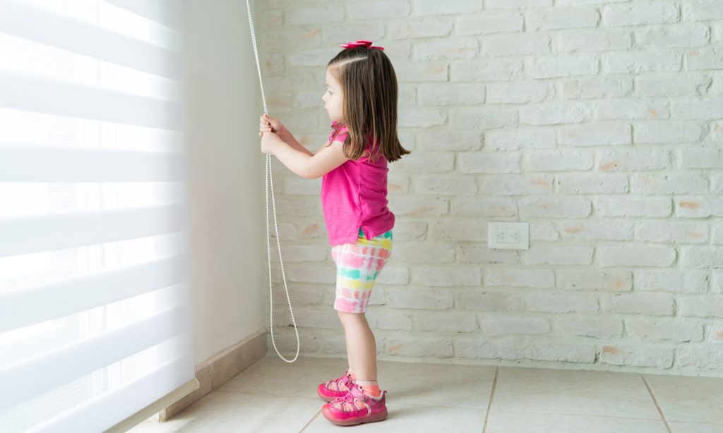 Little girl pulling a curtain cord